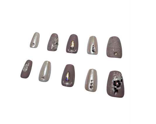 Set of decorative false nails with rhinestones on a white and purple background